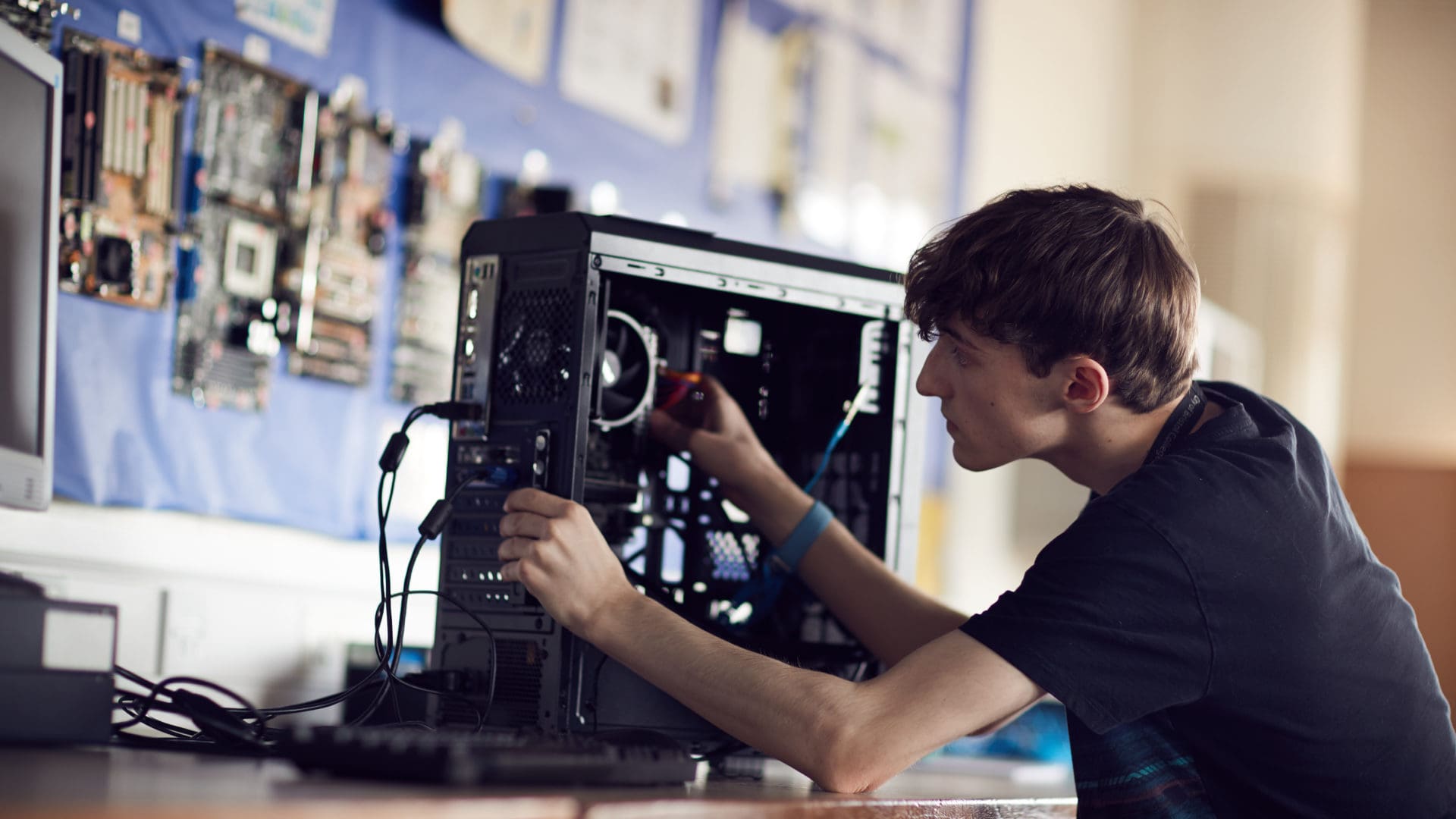 ϲ student focusing on fixing a computer on an IT course